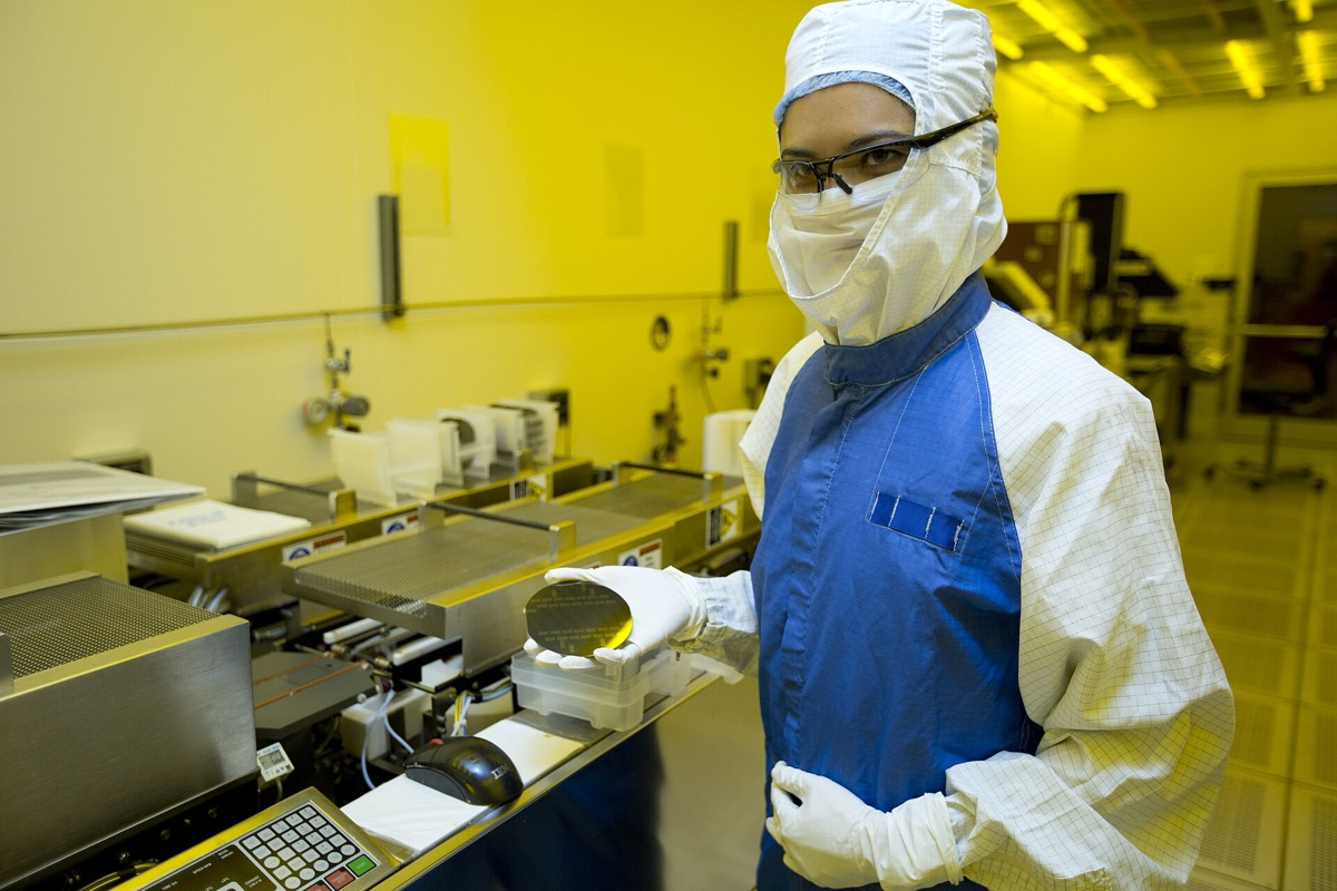 A researcher holds a shiny silicon semiconductor wafer, illustrating advanced electronic materials and the challenge of managing heat in modern chips (representative image; the study used a PMN-PT relaxor-ferroelectric crystal).