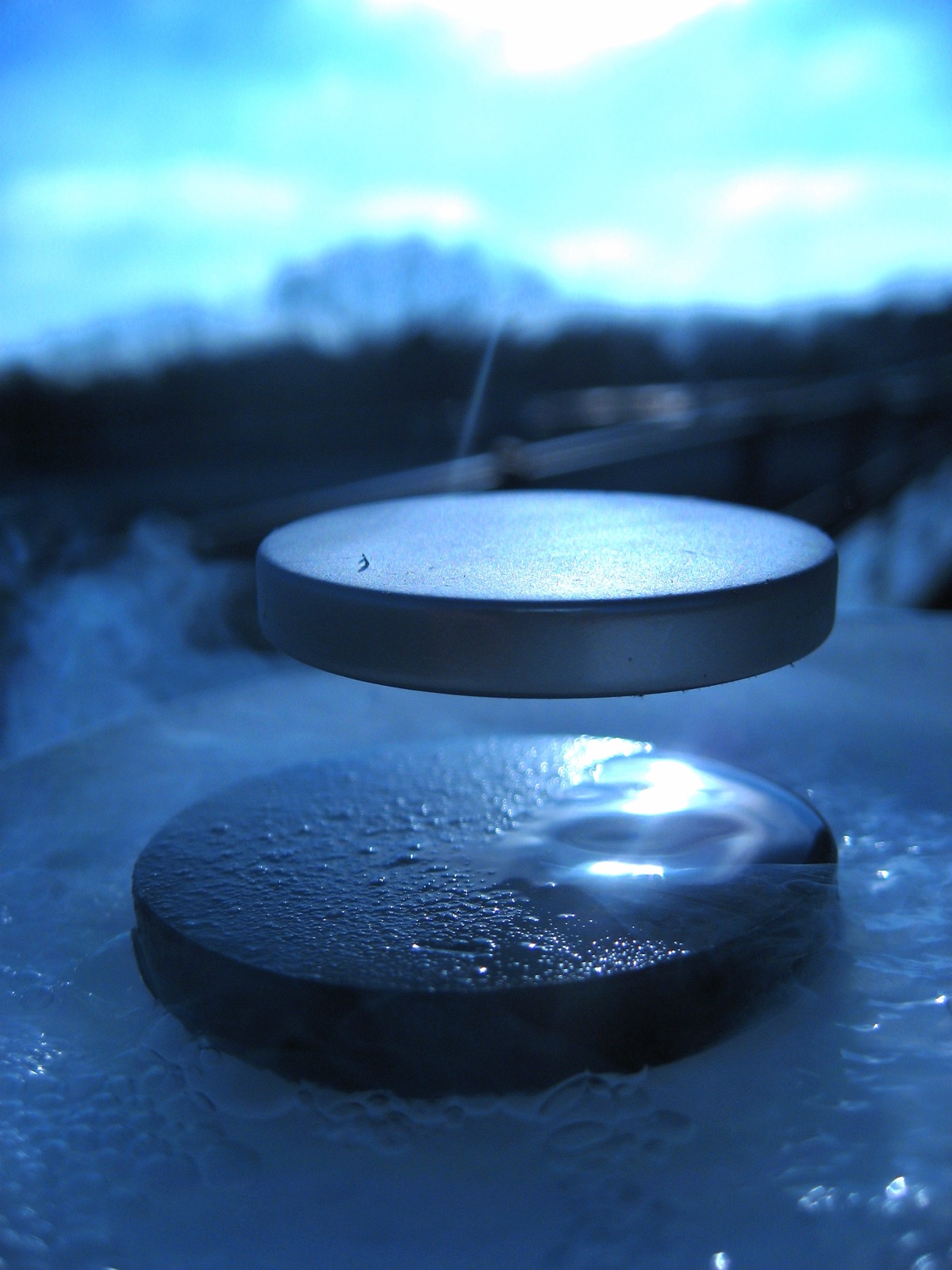 A small magnet levitating above a cooled YBa2Cu3O7 (YBCO) cuprate superconductor via the Meissner effect, illustrating research that boosts superconductivity in ultrathin YBCO films grown on nanofaceted substrates